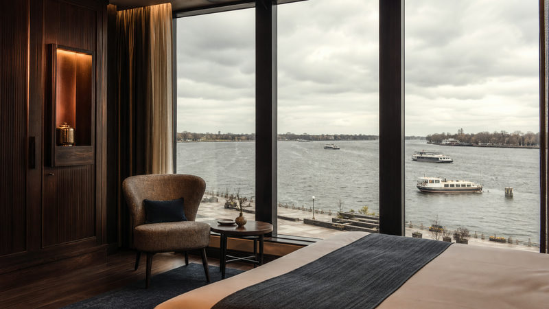 Hotelkamer met uitzicht over water en een pontsteiger in de verte