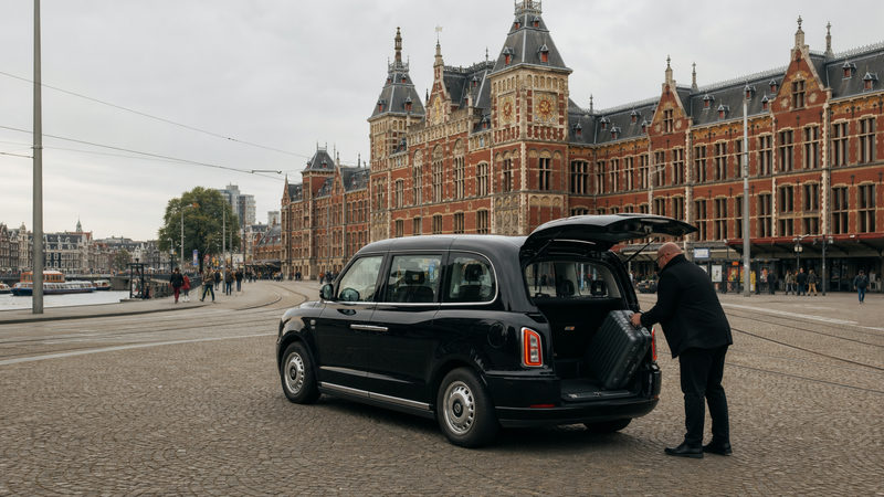 Taxi op het Stationsplein voor Amsterdam Centraal klaar voor een rit naar Schiphol